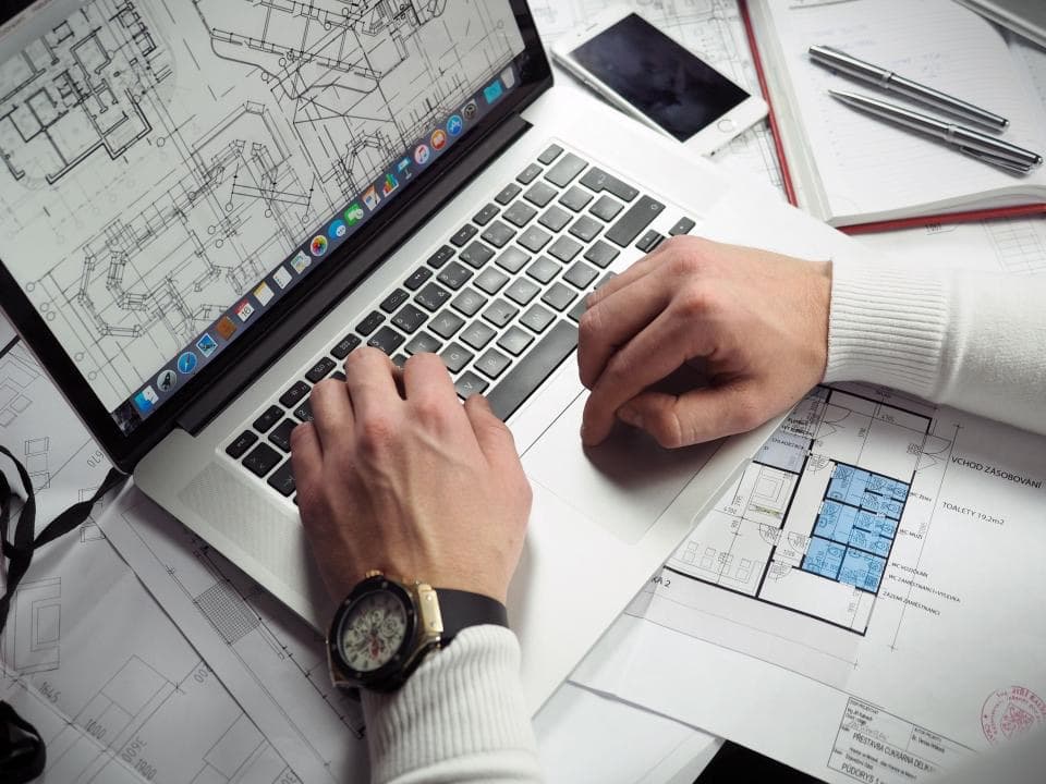 Arbeitsplatz mit Laptop und technischen Plänen